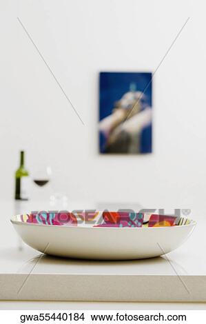 Close-up of a bowl on a dining table with a bottle of red wine in the background View Large Photo Image Picture - Close-up of a bowl on a dining table with a bottle of red wine in the background. Fotosearch