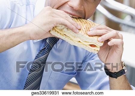 Close-up of a businessman eating a cheese sandwich View Large Photo Image Stock Image - Close-up of a businessman eating a cheese sandwich. Fotosearch