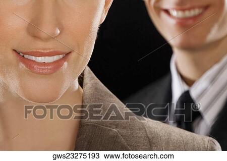 Close-up of a businesswoman smiling with a businessman behind her View Large Photo Image Stock Image - Close-up of a businesswoman smiling with a businessman behind her. Fotosearch