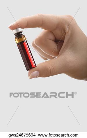 Picture - Close-up of a female doctor's hand holding a vial. Fotosearch