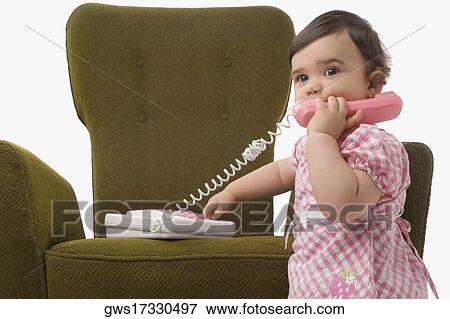 Close-up of a girl playing with a toy phone View Large Photo Image Stock Photo - Close-up of a girl playing with a toy phone. Fotosearch