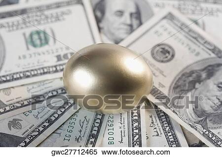 Stock Photography - Close-up of a golden egg on US paper currency. Fotosearch