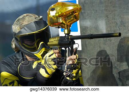 Stock Photo - Close-up of a mid adult man aiming with a paintball gun. Fotosearch