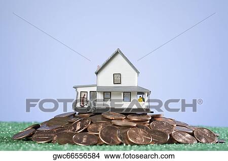 Picture - Close-up of a model home on a pile of coins. Fotosearch