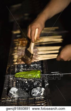 Stock Image - Close-up of a person's hand applying oil on meat, Nanjing, Jiangsu Province, China. Fotosearch