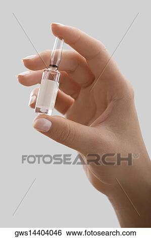Stock Photograph - Close-up of a person's hand holding a vial. Fotosearch