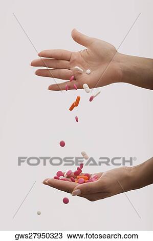 Stock Image - Close-up of a person's hand pouring pills on another hand. Fotosearch