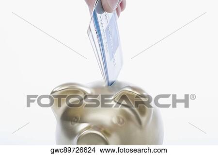 Close-up of a person's hand putting a credit card into a piggy bank View Large Photo Image Picture - Close-up of a person's hand putting a credit card into a piggy bank. Fotosearch