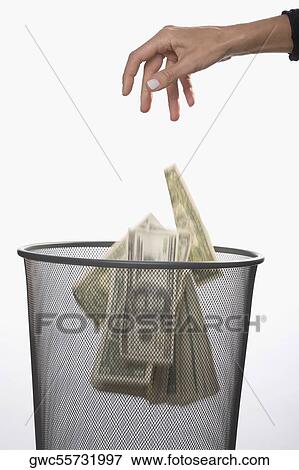 Close-up of a person's hand throwing US dollar bills in a garbage bin View Large Photo Image Stock Photo - Close-up of a person's hand throwing US dollar bills in a garbage bin. Fotosearch