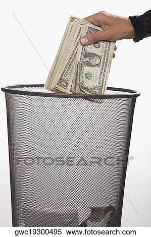 Close-up of a person's hand throwing US dollar bills in a garbage bin View Large Photo Image Stock Photography - Close-up of a person's hand throwing US dollar bills in a garbage bin. Fotosearch