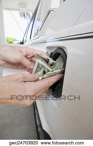 Close-up of a person's hands putting US paper currency in a gas tank of a car View Large Photo Image Stock Image - Close-up of a person's hands putting US paper currency in a gas tank of a car. Fotosearch