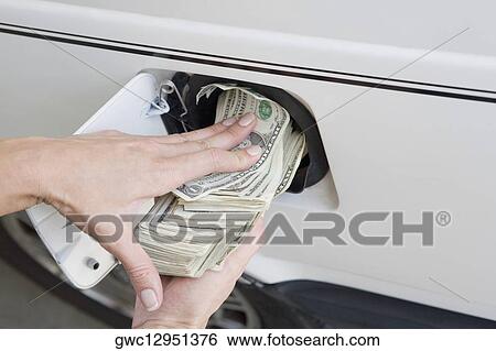 Close-up of a person's hands putting US paper currency in a gas tank of a car View Large Photo Image Stock Photograph - Close-up of a person's hands putting US paper currency in a gas tank of a car. Fotosearch