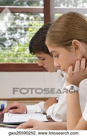 Close-up of a schoolgirl and a schoolboy studying together in a classroom View Large Photo Image Stock Image - Close-up of a schoolgirl and a schoolboy studying together in a classroom. Fotosearch