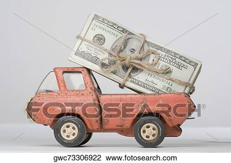 Stock Image - Close-up of a toy truck loading a bundle of paper currency. Fotosearch