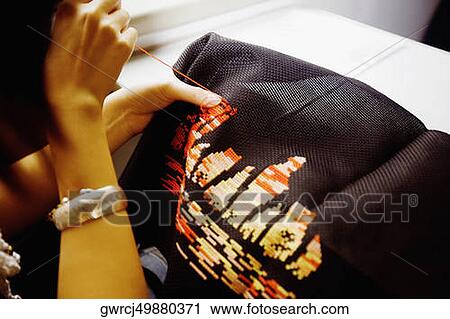 Stock Image - Close-up of a woman's hands embroidering, Shandong Province, China. Fotosearch