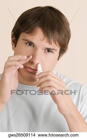 Close-up of a young man putting nasal spray drops in his nose View Large Photo Image Picture - Close-up of a young man putting nasal spray drops in his nose. Fotosearch