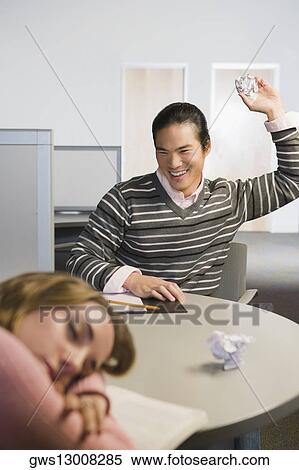 Close-up of a young woman napping and a young man throwing a crumpled paper on her View Large Photo Image Stock Photography - Close-up of a young woman napping and a young man throwing a crumpled paper on her. Fotosearch