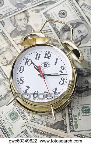Stock Image - Close-up of an alarm clock on paper currency. Fotosearch