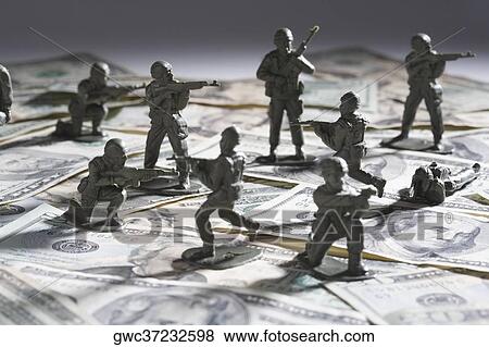 Stock Photo - Close-up of plastic toys fighting on paper currency. Fotosearch