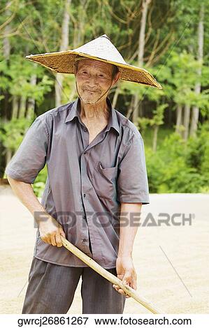 Stock Photo - Farmer holding a rake in a field, Zhigou, Shandong Province, China. Fotosearch