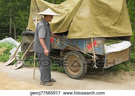 Stock Photo - Farmer standing beside a vehicle trailer, Zhigou, Shandong Province, China. Fotosearch