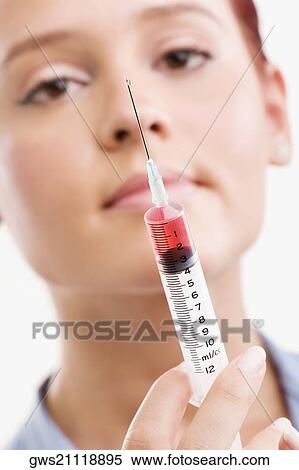 Stock Photography - Female doctor holding a syringe. Fotosearch
