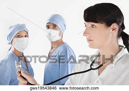 Female doctor with two surgeons in the background View Large Photo Image Stock Photograph - Female doctor with two surgeons in the background. Fotosearch