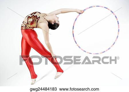 Stock Image - Female gymnast practicing with a plastic hoop. Fotosearch