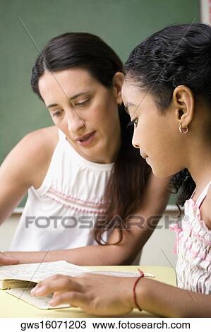 Stock Image - Female teacher teaching her student in a classroom. Fotosearch