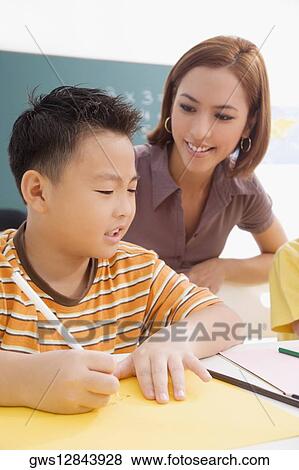 Stock Photo - Female teacher teaching her student in a classroom. Fotosearch
