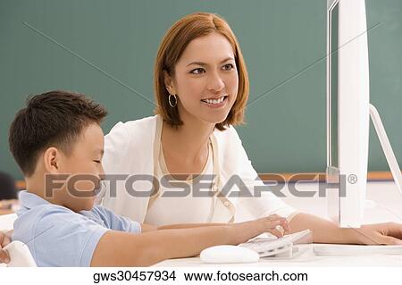 Female teacher with her student in front of a desktop PC View Large Photo Image Picture - Female teacher with her student in front of a desktop PC. Fotosearch