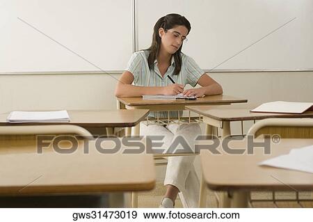 Stock Photo - Female teacher writing in a classroom. Fotosearch