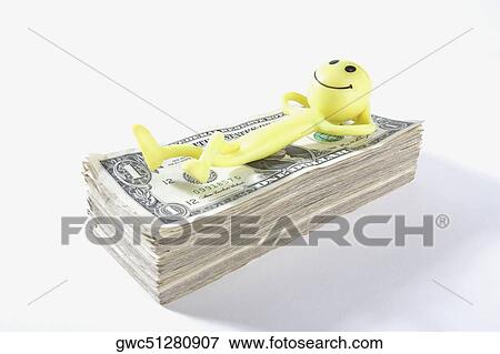 Stock Photo - Figurine of a man lying on a wad of US dollar bills. Fotosearch