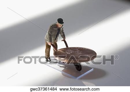 Figurine of a manual worker carrying a coin on a wheelbarrow View Large Photo Image Picture - Figurine of a manual worker carrying a coin on a wheelbarrow. Fotosearch