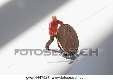 Figurine of a manual worker carrying a coin on a push cart View Large Photo Image Stock Photo - Figurine of a manual worker carrying a coin on a push cart. Fotosearch