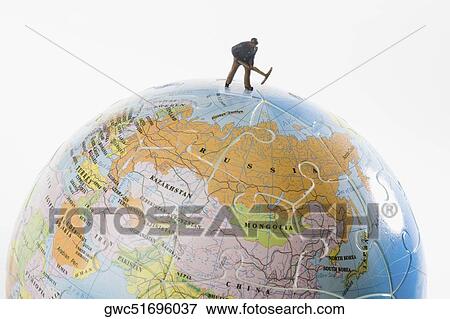 Figurine of a manual worker working on a globe View Large Photo Image Stock Photo - Figurine of a manual worker working on a globe. Fotosearch