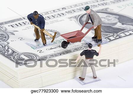 Stock Image - Figurines of manual workers with US paper currency. Fotosearch