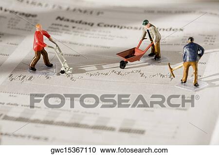 Stock Image - Figurines of manual workers working on a financial newspaper. Fotosearch