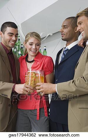 Stock Image - Four business executives toasting with glasses of beer in a party. Fotosearch