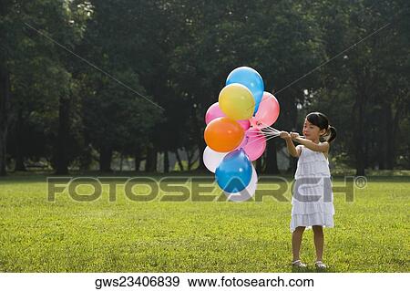 Stock Photo - Girl holding balloons in a park. Fotosearch