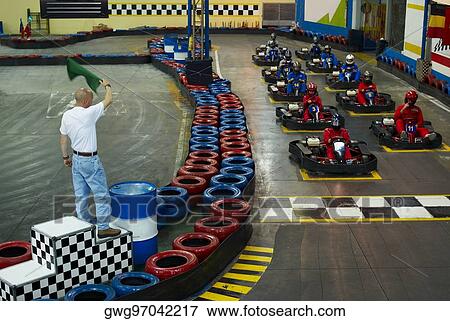 Stock Photo - High angle view of go-cart racer at starting line with a man waving a flag. Fotosearch