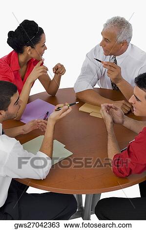Stock Image - High angle view of three businessmen and a businesswoman discussing in a meeting. Fotosearch