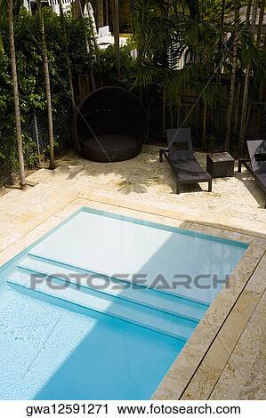 Stock Image - Lounge chairs at the poolside. Fotosearch