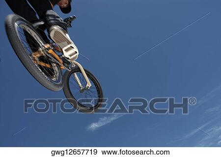 Low angle view of a young man jumping with his bicycle View Large Photo Image Stock Photo - Low angle view of a young man jumping with his bicycle. Fotosearch