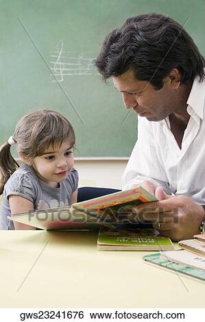 Male teacher teaching his student in a classroom View Large Photo Image Stock Photograph - Male teacher teaching his student in a classroom. Fotosearch