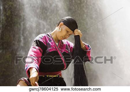 Stock Photography - Mature woman holding her wet hair, Jinkeng Terraced Field, Guangxi Province, China. Fotosearch