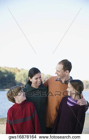 Picture - Mid adult couple with their two children standing together and smiling. Fotosearch