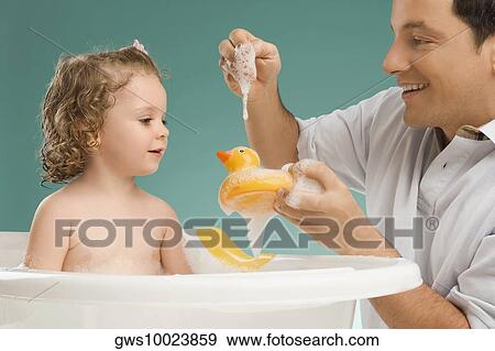 Stock Photo - Mid adult man playing with his daughter and smiling. Fotosearch