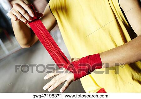 Stock Image - Mid section view of a male boxer wrapping his hand with a bandage. Fotosearch