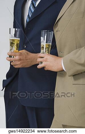 Mid section view of two businessmen holding glasses of beer in a party View Large Photo Image Picture - Mid section view of two businessmen holding glasses of beer in a party. Fotosearch